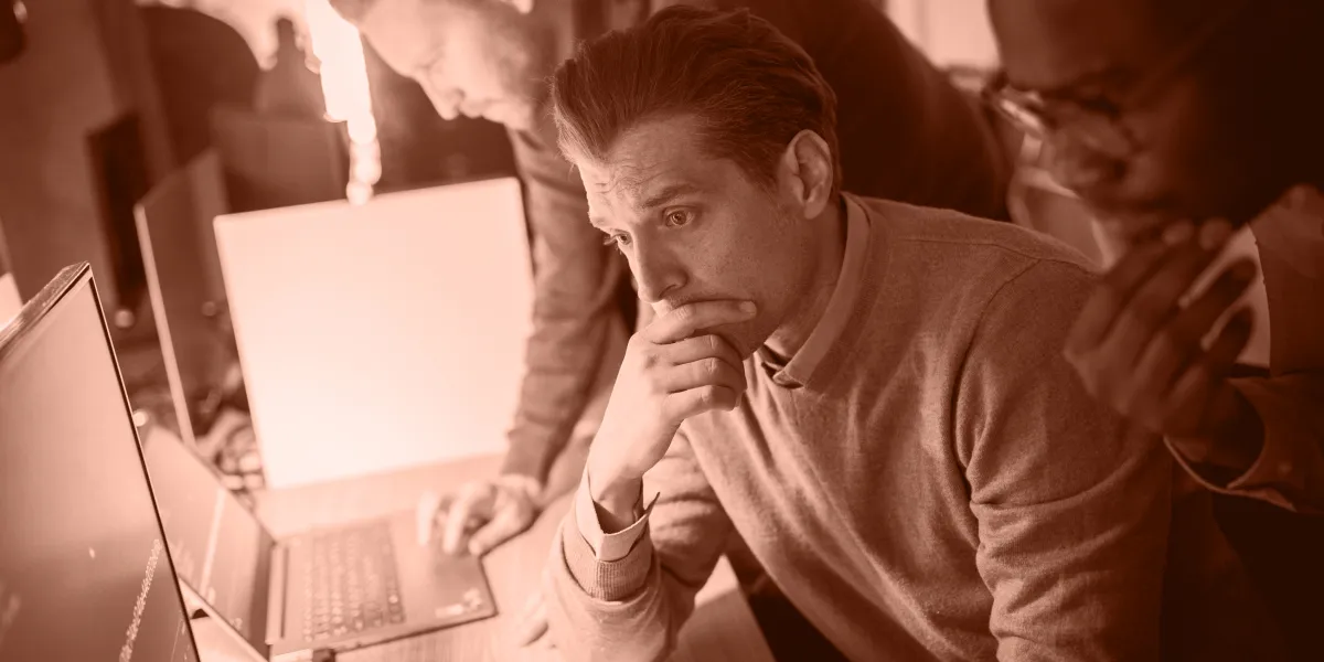 Tre personer fokuserade på att analysera och diskutera lösningar inom IT-säkerhet vid en dator