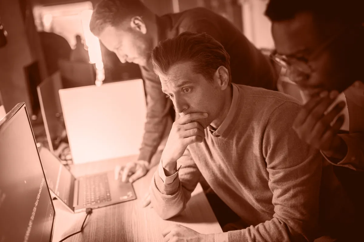 Tre personer fokuserade på att analysera och diskutera lösningar inom IT-säkerhet vid en dator